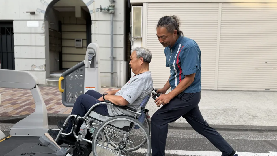 車いすの利用者様を車両まで介助する様子